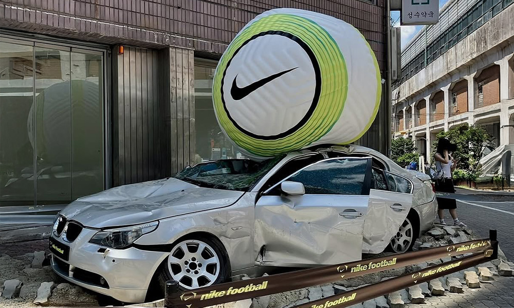 Giant Nike soccer ball crushing the roof of a BMW